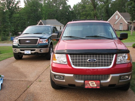 1991 Ford Bronco - Two Ford trucks, a red Expedition and a green F-150, are parked in a driveway.
