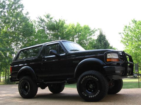 1967 Ford Mustang - This black Ford Bronco is shown from a three-quarter front angle, with a brush guard and off-road tires visible.