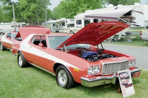 1976 Ford Ranchero - Two red and white 1976 Ford Rancheros are displayed on grass with RVs in the background.