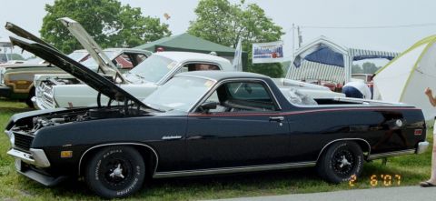 1976 Ford Ranchero - A black 1972 Ford Ranchero is displayed with its hood open at an outdoor car show, with other vehicles and tents in the background.