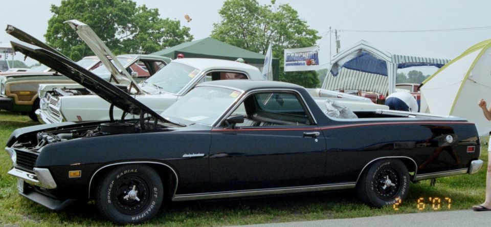 Black 1972 Ranchero with hood open, parked at an outdoor event