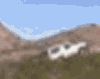 1996 Ford Bronco - A light-colored SUV appears on a dirt trail amid brushy, rocky terrain with a hazy mountain ridge in the background; the image is heavily b…