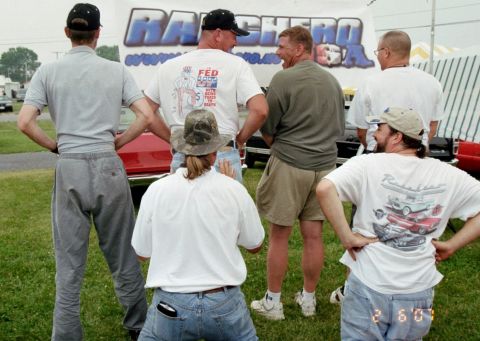 1976 Ford Ranchero - Men gather around a red vehicle at an outdoor event, with a banner indicating a focus on 'Ranchero USA'.