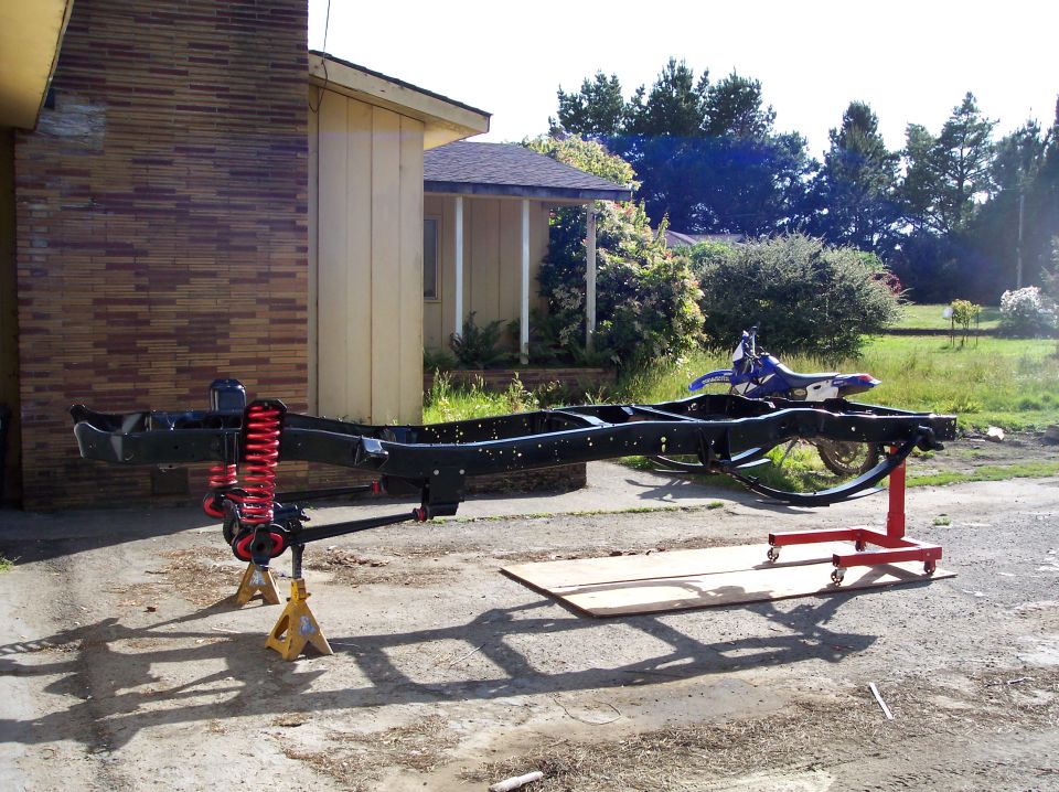 Truck frame on jack stands, dirt bike in background