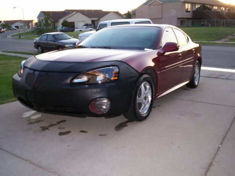 2004 Pontiac Grand Prix - A maroon 2004 Pontiac Grand Prix is parked on a driveway, partially covered by a car bra.