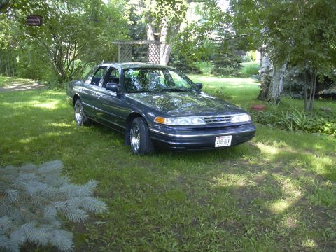 1996 Ford Crown Victoria - 1996 Ford Crown Victoria parked in a grassy yard with trees in the background.