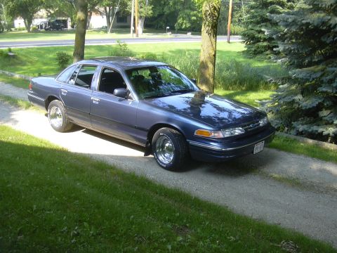 1996 Ford Crown Victoria - Blue 1996 Ford Crown Victoria sits on a gravel driveway next to a lawn and trees.