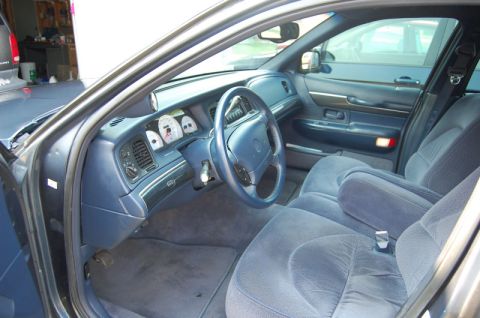 1985 Mercury Grand Marquis - The interior of a blue sedan features plush cloth seats and a clear view of the dashboard instrumentation.