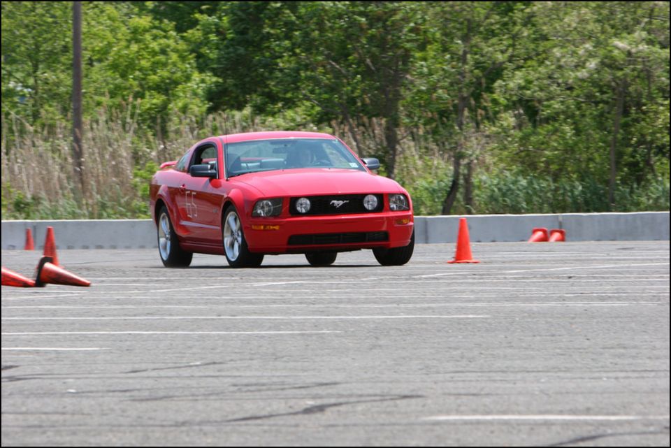 Red Ford Mustang on a race track with orange cones