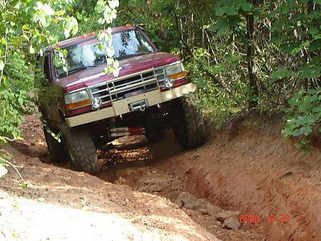 1995 Ford Bronco - This maroon Ford Bronco navigates a challenging off-road trail with its front end angled towards the camera.