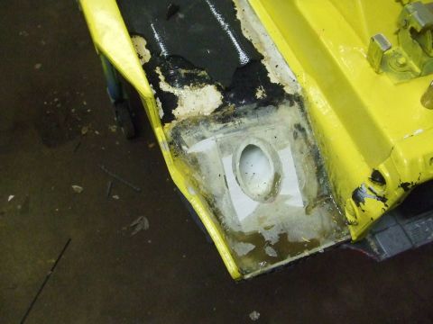 1995 Ford Mustang - This image shows a close-up of a yellow car's body panel undergoing repair work, revealing damaged sections and filler material.