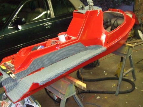 1995 Ford Mustang - A red jet ski body is undergoing repairs or restoration, supported by sawhorses in a workshop setting.