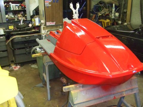 1995 Ford Mustang - A red jet ski body is being worked on in a cluttered garage setting.