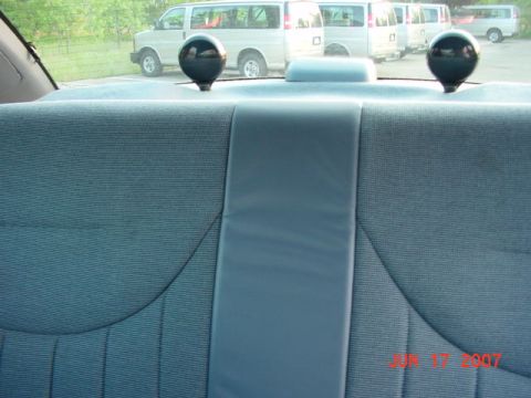 2003 Ford Crown Victoria - View from the rear seat shows two black sphere-shaped objects and vans parked outside.