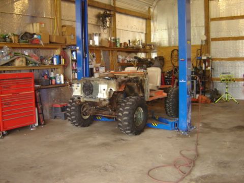 1992 Ford Bronco - This vehicle is in a garage, raised on a lift with its front end disassembled for repairs.