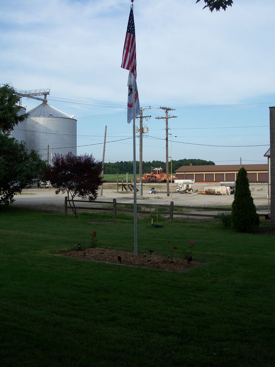 Scene with American and Illinois flags, grain silos, and farm buildings