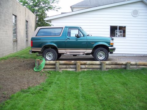 1996 Ford Bronco - This 1990s Ford Bronco is seen parked on a slight incline next to a white building.