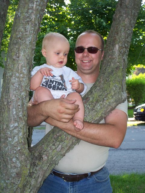 1996 Ford Bronco - A man and a baby are photographed outdoors, positioned between two large tree trunks.