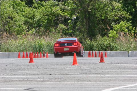 2001 Mercury Grand Marquis - Red Ford Mustang driving through an autocross course on a sunny day.