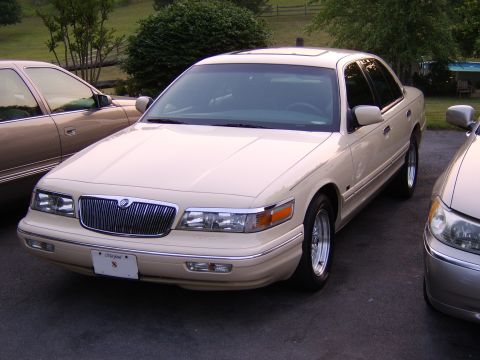 1996 Mercury Grand Marquis - A 1996 Mercury Grand Marquis is parked in a driveway with another vehicle nearby.