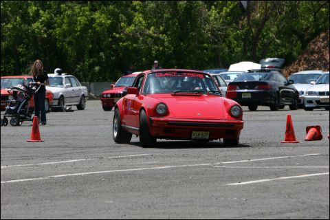 2001 Mercury Grand Marquis - A red Porsche 911 navigates an autocross course, with other vehicles and spectators visible in the background.