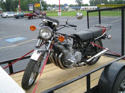 2004 Ford F-150 - A motorcycle is secured with straps on a wooden trailer, ready for transport.