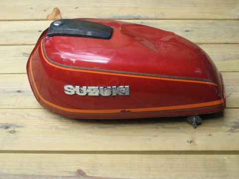 2004 Ford F-150 - A red Suzuki motorcycle fuel tank with orange pinstriping sits on a wooden surface.