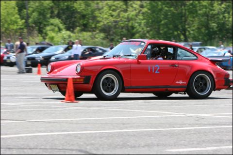 2001 Mercury Grand Marquis - A red Porsche 911 with racing numbers is seen on a track, with other cars in the background.
