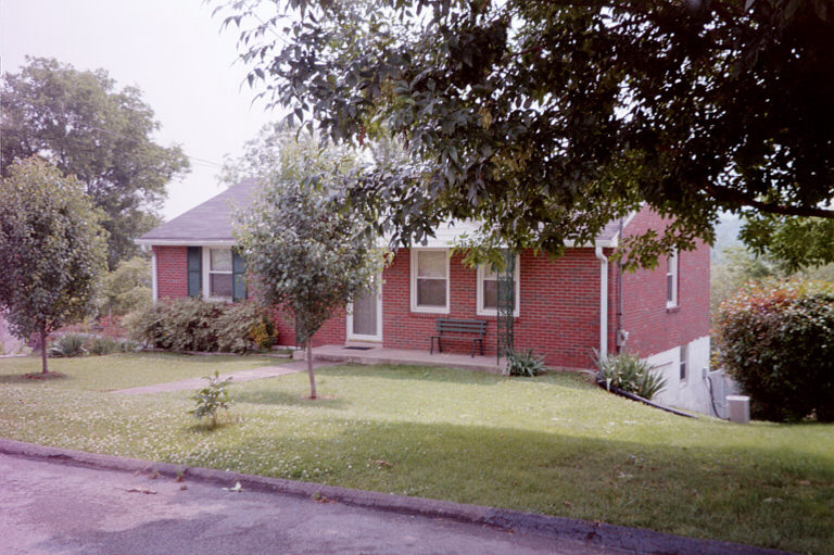 Brick house with green shutters and a lawn
