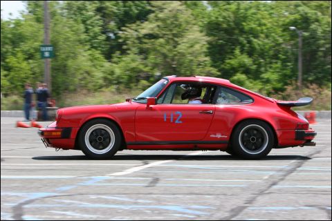 2001 Mercury Grand Marquis - A red Porsche 911 with racing decals and number 112 competes on a sunny day.