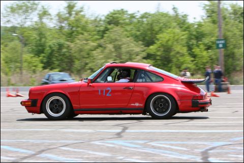 2001 Mercury Grand Marquis - A red Porsche 911 with racing number 112 competes on a track, with another vehicle blurred in the background.