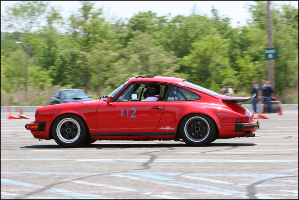 Red Porsche 911 with racing number 112 on side, racing spoiler