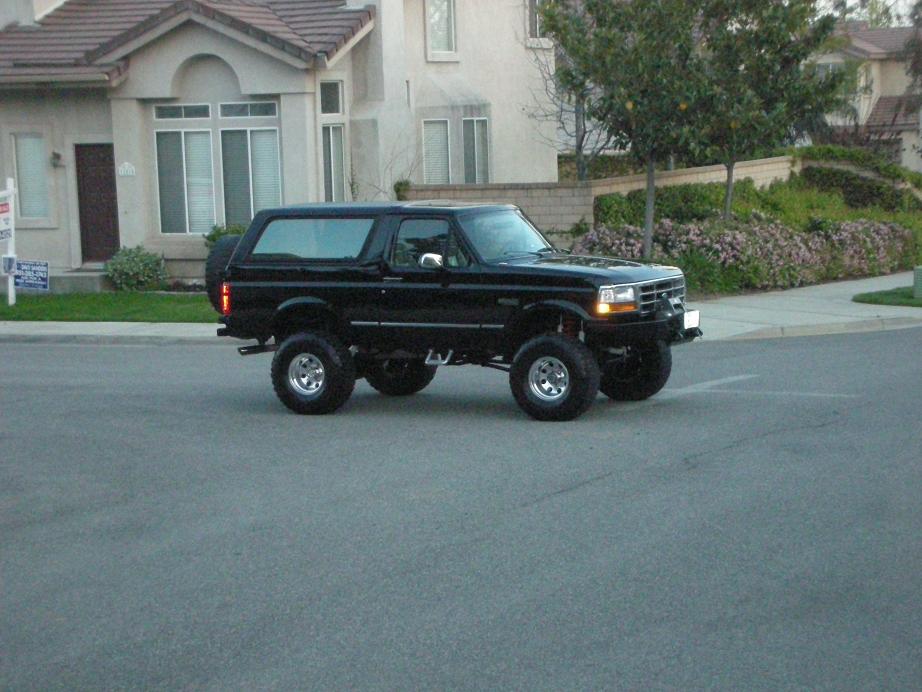 Black lifted 1996 Ford Bronco driving on a suburban street