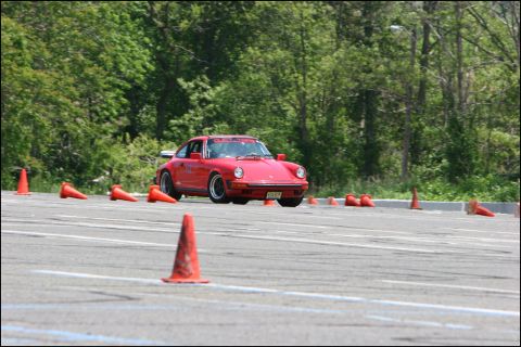 2001 Mercury Grand Marquis - A red Porsche 911 navigates a course marked by orange cones on a sunny day.