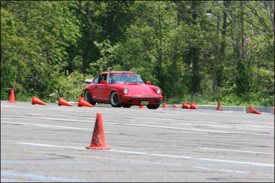 Red Porsche 911 driving through cones on a track