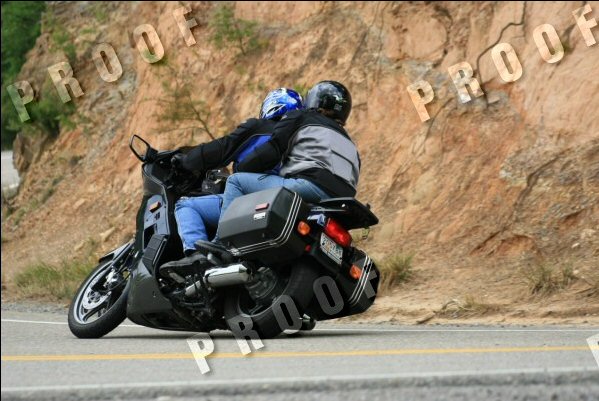 Motorcycle with two riders on a road with a rocky hillside