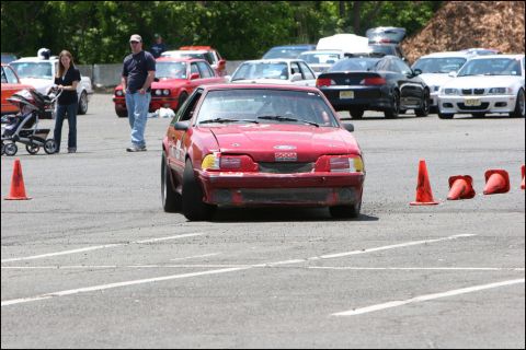 2001 Mercury Grand Marquis - A red Ford Mustang navigates an autocross course with traffic cones visible.