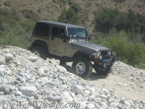 1987 Suzuki Samurai - A tan Jeep Wrangler TJ navigates a rocky, off-road path.