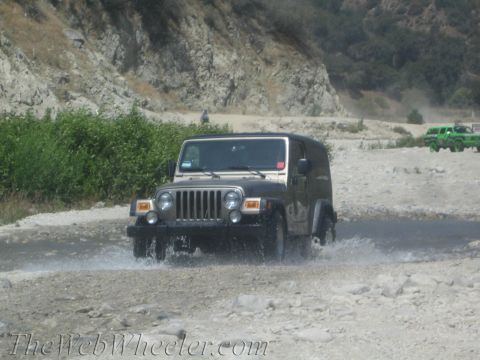 1987 Suzuki Samurai - A Jeep Wrangler navigates a shallow water crossing with a second Jeep visible in the distance.