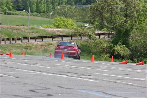 2001 Mercury Grand Marquis - Red sports coupe drifts around cones on a race track during an event.