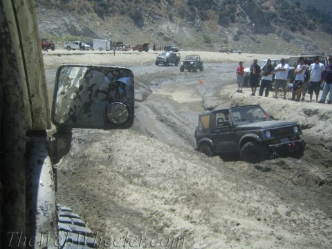 1987 Suzuki Samurai - A Suzuki Samurai navigates a muddy off-road course with spectators watching.