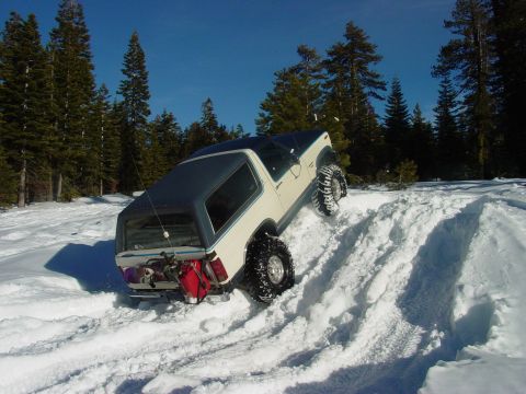 1986 Ford Bronco - Ford Bronco navigates a snowy trail, tires digging into the deep snow.