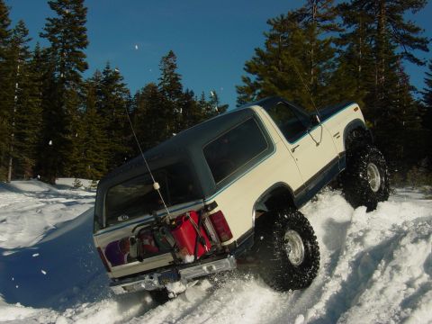 1986 Ford Bronco - This modified Ford Bronco navigates a steep, snow-covered slope with large off-road tires.