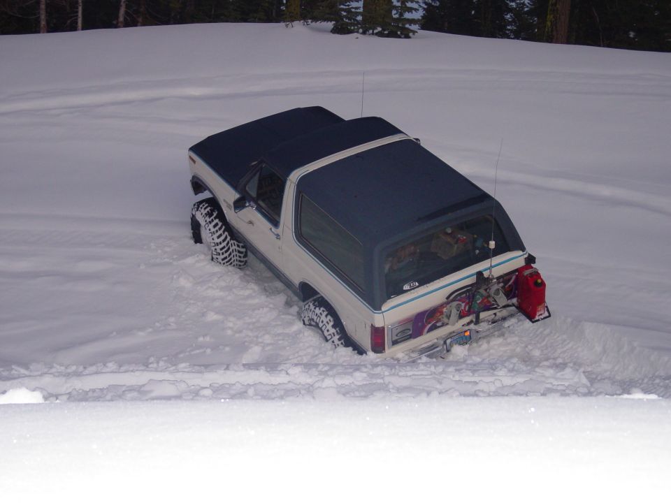 1986 Ford Bronco stuck in deep snow, rear view with gas can mounted on spare tire carrier