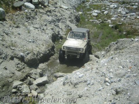 1987 Suzuki Samurai - A Suzuki Samurai navigates a challenging off-road course with rocky terrain and water obstacles.