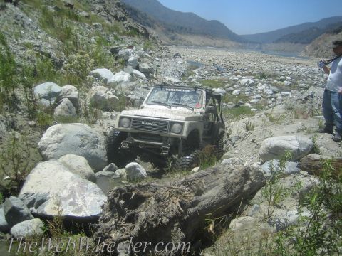 1987 Suzuki Samurai - A Suzuki Samurai tackles a challenging off-road course with large rocks and debris.