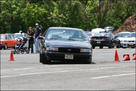 2001 Mercury Grand Marquis - A black Chevrolet sedan navigates an autocross course, with other vehicles and spectators in the background.