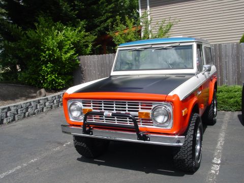 1973 Ford Bronco - Front view of a two-tone 1973 Ford Bronco with an orange grille surround and black hood.