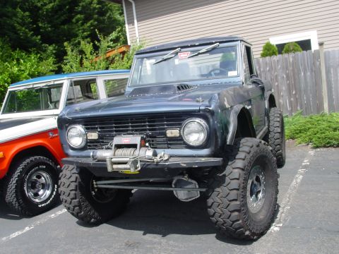 1973 Ford Bronco - A modified 1973 Ford Bronco with a winch and off-road tires is parked next to another Bronco.