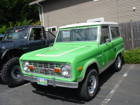 1973 Ford Bronco - A bright green 1973 Ford Bronco is parked next to another vehicle at an outdoor gathering.